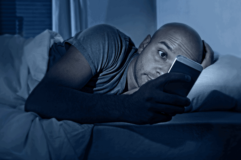 אדם קורא בסמארטפון בלילה ונחשף ל אור כחול